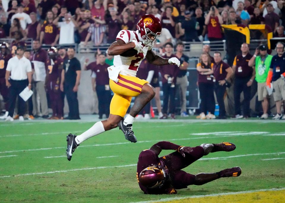 Sep 23, 2023; Tempe, Arizona, USA; USC Trojans wide receiver <a class="link " href="https://sports.yahoo.com/ncaaf/players/315181" data-i13n="sec:content-canvas;subsec:anchor_text;elm:context_link" data-ylk="slk:Brenden Rice;sec:content-canvas;subsec:anchor_text;elm:context_link;itc:0">Brenden Rice</a> (2) jumps over Arizona State Sun Devils defensive back Demetries Ford (4) to score a touchdown in the first half at Mountain America Stadium. Mandatory Credit: Rob Schumacher-Arizona Republic