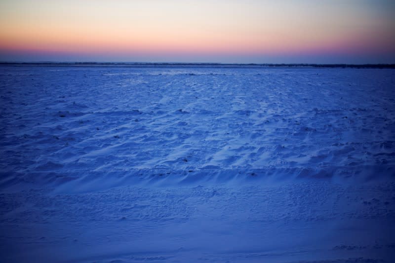 The sun sets over snow-covered river in Tongjiang