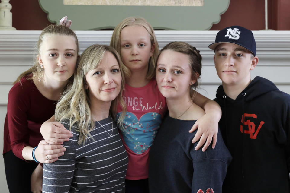 In this Oct. 9, 2019, photo, Donya Grant, second from left, poses for a photo with her children, Rowyn, 11, left, Mabry, 8, center, Hadley, 16, second from right, and Kemper, 14, right, in their home in Monroe, Wash. The family joined a lawsuit against the Monroe School District and others, alleging that the district failed to adequately respond to PCBs, or polychlorinated biphenyls, at the Sky Valley Education Center, a K-12 public school. Grant has homeschooled her children since they left Sky Valley in 2016 for health reasons that they believe were related to the toxic chemicals. (AP Photo/Ted S. Warren)