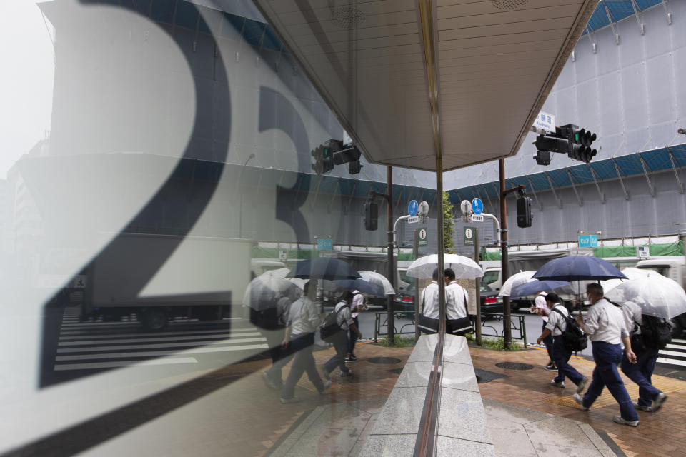 People walk by screens showing Japan's Nikkei 225 index at a securities firm in Tokyo on Friday, Sept. 25, 2020. Asian shares advanced Friday, cheered by a modest rally on Wall Street and rising hopes for fresh stimulus for the U.S. economy.(AP Photo/Hiro Komae)