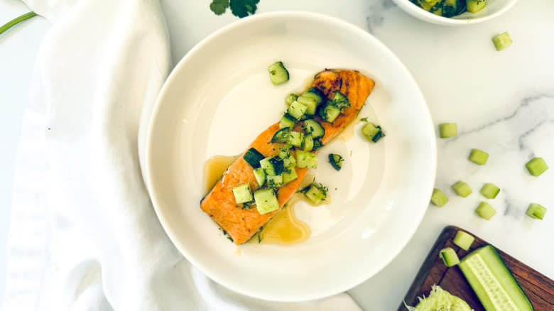 salmon with cucumber topping on white plate