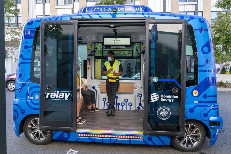 Deployment Manager Jason Peres, center, explains how Relay, an electric autonomous vehicle, works to new riders in Fairfax, Va., Thursday, Oct. 22, 2020. The future of transportation arrived in northern Virginia, looking like a big blue toaster on wheels that can seat six and drive itself through the region’s notorious traffic. State and local officials debuted the Relay system Thursday, an all-electric, autonomous vehicle that will provide free shuttle rides back and forth from the Dunn Loring Metrorail stop to the bustling Mosaic District in Fairfax County, Va. (AP Photo/Jacquelyn Martin)