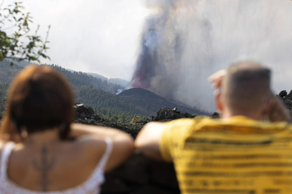 People watch as lava flows from an eruption of a volcano near El Paso on the island of La Palma in the Canaries, Spain, of Monday, Sept. 20, 2021. Lava continues to flow slowly from a volcano that erupted in Spain's Canary Islands off northwest Africa. The head of the islands' regional government says Monday he expects no injuries to people in the area after some 5,000 were evacuated. (AP Photo/Gerardo Ojeda)