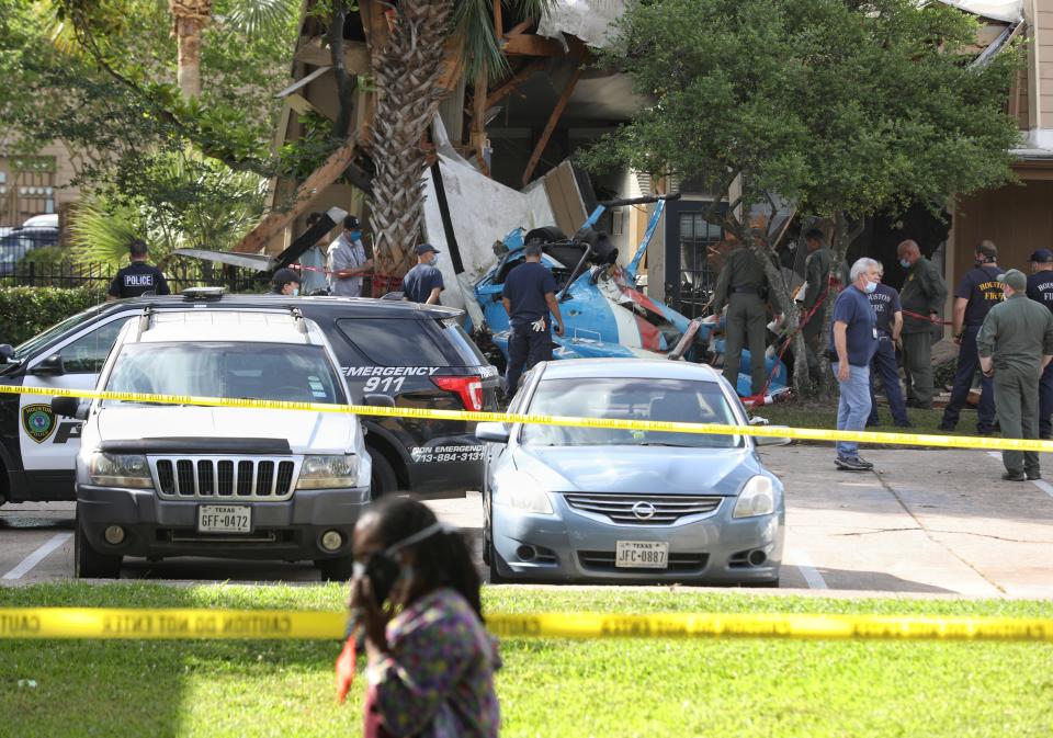 Authorities investigate the scene of a helicopter crash at an apartment complex in Houston, Saturday, May 2, 2020. Houston Police Chief Art Acevedo says the helicopter was carrying a pilot and a tactical flight officer when it went down at an apartment complex in north Houston around 2 a.m. Saturday. The cause of the crash wasn't immediately known. (Jon Shapley/Houston Chronicle via AP)