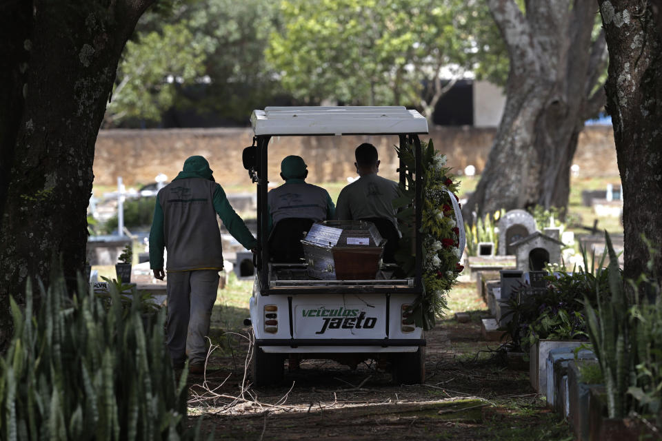 Cemetery workers transport the coffin that contains the remains of Jose Valdelirio believed to have died from the new coronavirus, to a burial site at the Campo da Esperanca cemetery in the Taguatinga neighborhood of Brasilia, Brazil, Wednesday, March 3, 2021. The number of COVID-19 cases in Brazil is still surging, with a new record high of deaths reported on Tuesday. (AP Photo/Eraldo Peres)