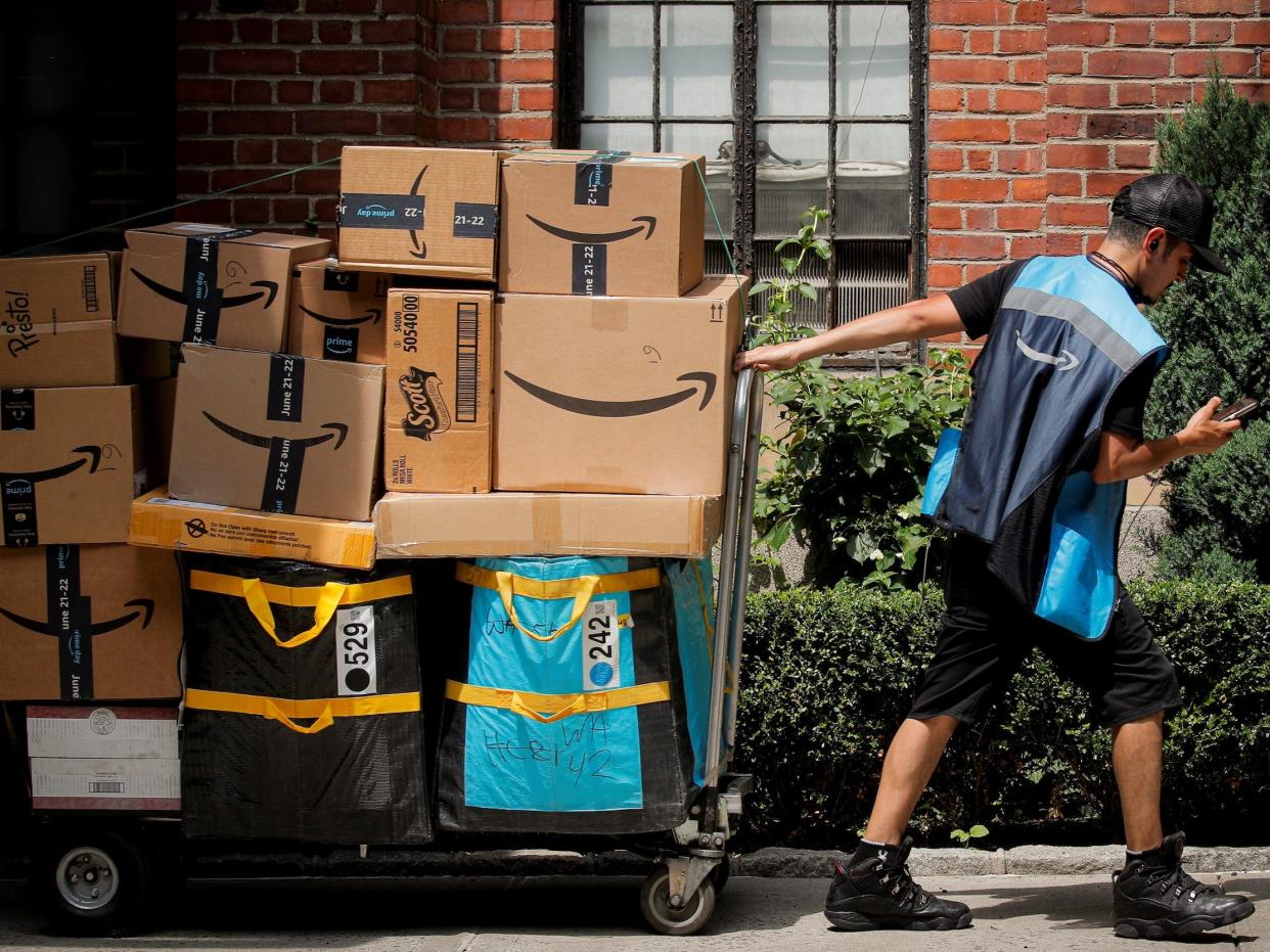 An Amazon delivery worker pulls a delivery cart full of packages during its annual Prime Day promotion in New York