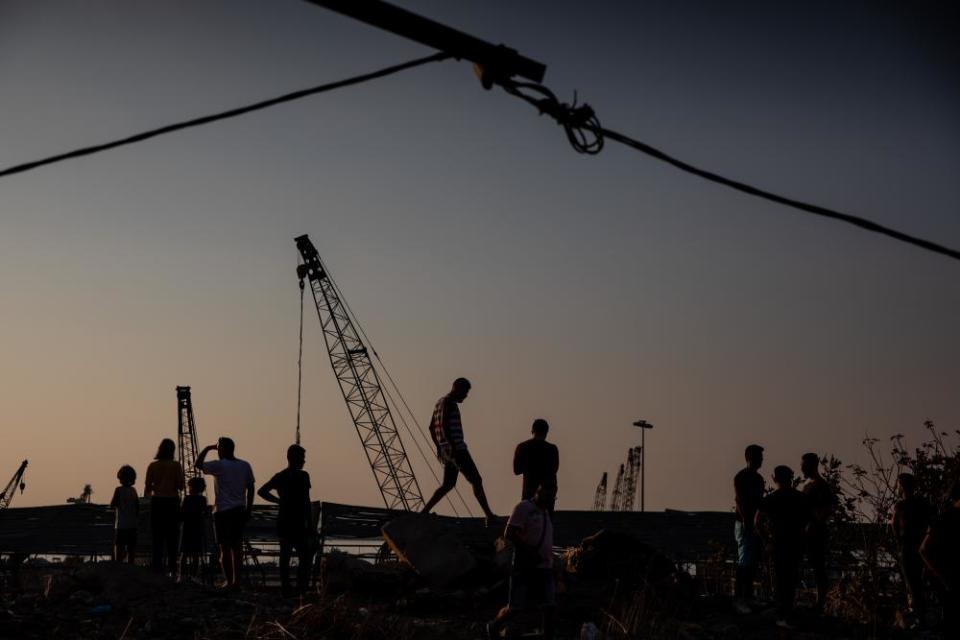 People stop to view the destroyed port in Beirut