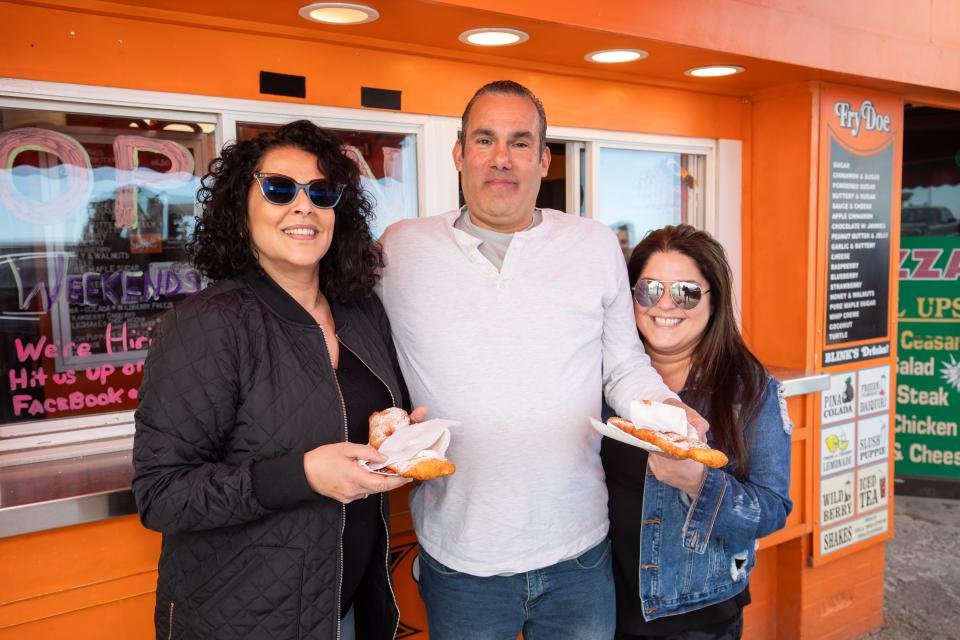 Andrea, Daryl, and Jenn from Lawrence, Massachusetts, enjoy sugared fried dough. The three have made it a sweet tradition “a million times” over to come to Blink’s Fry Doe at Hampton Beach.