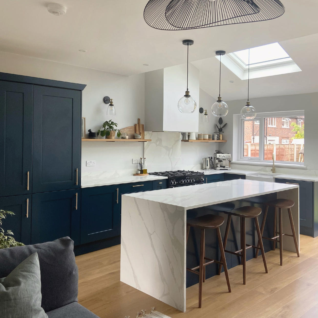  Kitchen with blue units and marble-effect waterfall work surface on breakfast bar. 