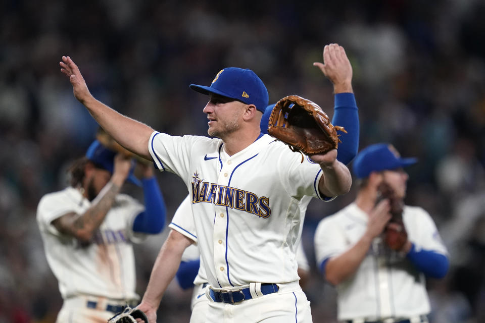 Seattle Mariners third baseman Kyle Seager waves to fans as teammates applaud behind as he leaves a baseball game against the Los Angeles Angels in the ninth inning Sunday, Oct. 3, 2021, in Seattle. (AP Photo/Elaine Thompson)