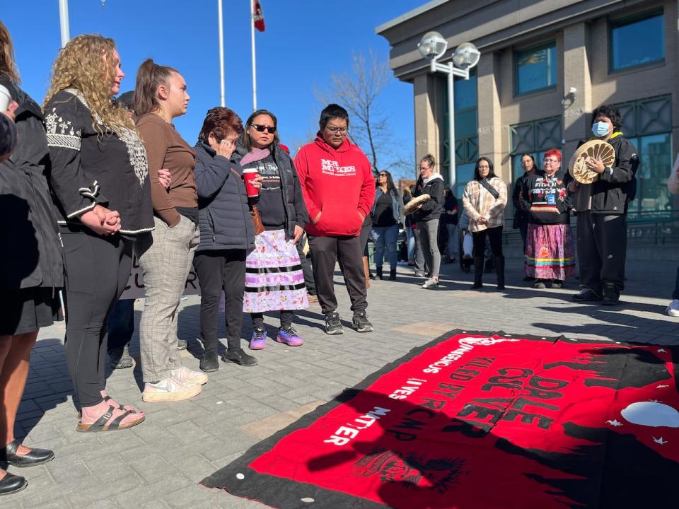 Culver's family members stand silent as a drum group plays around them in advance of Friday's court hearing.