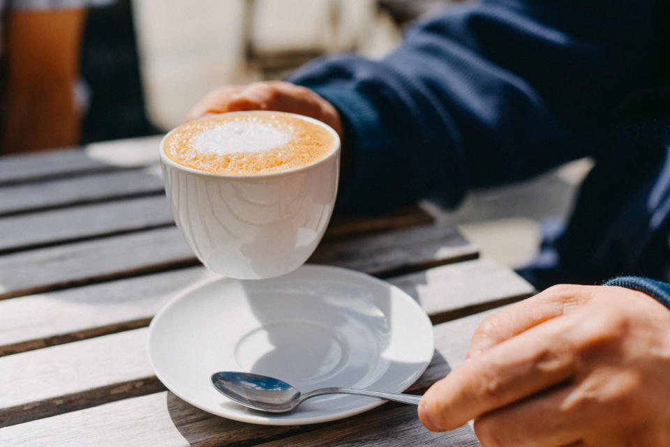 A man is holding up his cappuccino