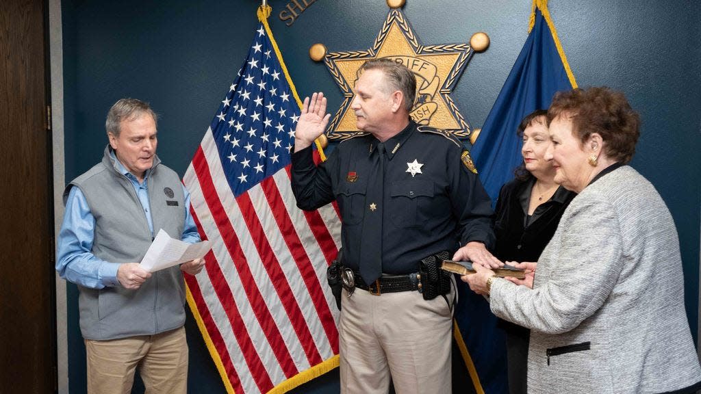 Sheriff Jay Long takes oath from Judge Craig Marcotte while his wife and mother hold the bible.