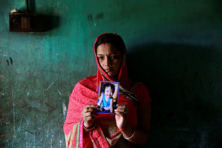 Rinki Singh, 31, holds a photo of her daughter Aarushi, 6, who died in the intensive care unit (ICU) of the Baba Raghav Das hospital in the Gorakhpur district, India August 14, 2017. REUTERS/Cathal McNaughton