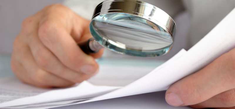 A magnifying glass being held over some paperwork.