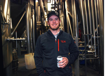 In this Nov. 18, 2014 photo, 10 Barrel Brewing Co. partner Garrett Wales poses in the company's brewery, in Bend, Ore. As it grew from a struggling timber town to an outdoor recreation destination, Bend, Ore., has seen an explosion of breweries, making it one of the top beer towns in the country. When 10 Barrel announced it was being bought by the world's biggest brewer, Anheuser-Busch Inbev, many local beer lovers felt betrayed. (AP Photo/Jeff Barnard)