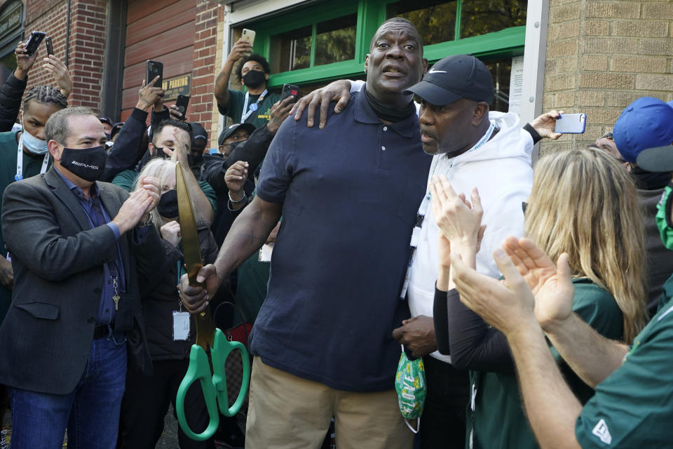 Shawn Kemp, center left, a former NBA basketball player for the Seattle SuperSonics and several other teams, hugs his former teammate and basketball Hall-of-Famer Gary Payton, center right, Friday, Oct. 30, 2020, after Kemp cut the ribbon for Shawn Kemp's Cannabis, the marijuana dispensary he owns with several business partners in downtown Seattle. (AP Photo/Ted S. Warren)