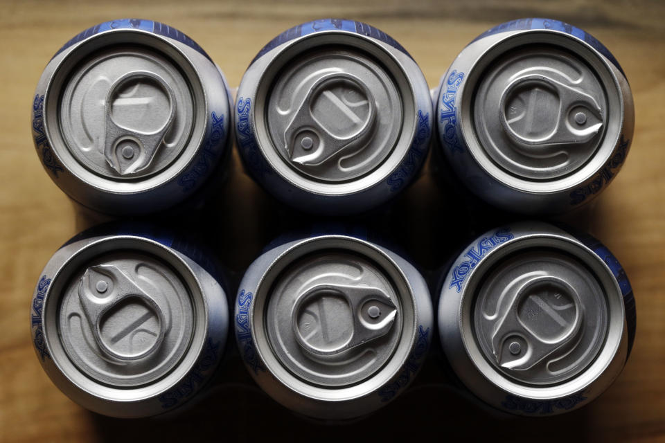 In this Monday, June 3, 2013 photo, cans of Helles Golden Lager with a 360 Lid are displayed at the Sly Fox Brewing Company, in Pottstown, Pa. Brewers and consumers debate using bottles or cans, innovation of the age-old staple continues as breweries seek to differentiate themselves on expanding beer shelves. Budweiser is selling a bowtie-shaped can that mirrors its iconic logo, Miller Lite is sold in a punch-top can, Sam Adams Boston Lager comes in cans designed to improve taste and now Sly Fox Brewing Co. is selling beer in "topless" cans with a peel-back lid that essentially turns it into a glass. (AP Photo/Matt Rourke)