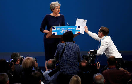 A member of the audience hands a P45 form (termination of employment tax form) to Britain's Prime Minister Theresa May as she addresses the Conservative Party conference in Manchester, October 4, 2017. REUTERS/Phil Noble