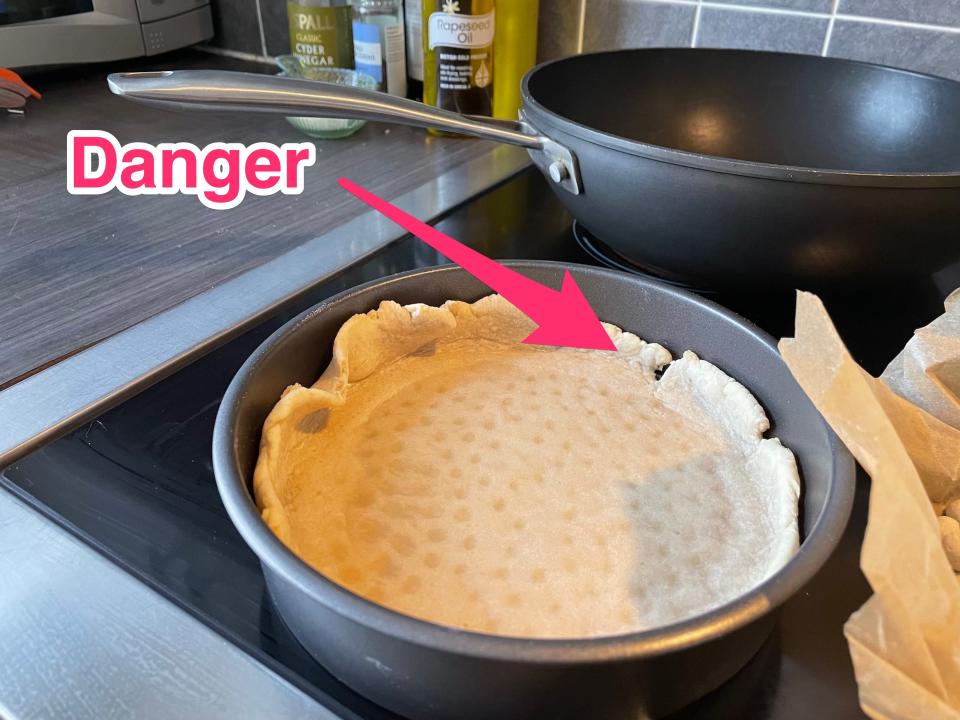 Blind-baked shortcrust pastry in its tin, with an arrow marking "danger" where the crust has a gap.