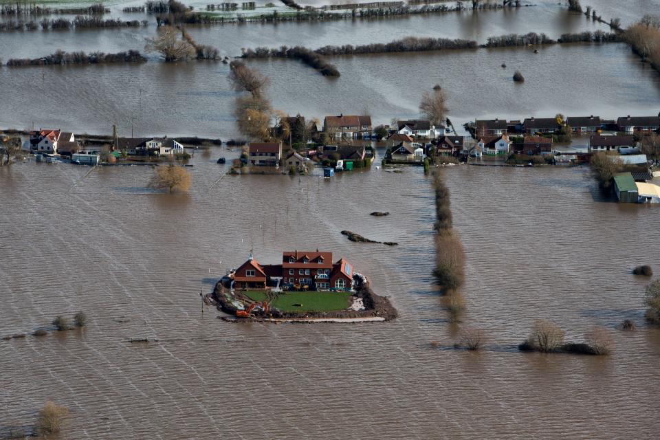 Flood waters inundate the area as one house stands alone and dry near the flooded village of Moorland in Somerset, southwest England, Thursday Feb. 13, 2014. The house is owned by Sam Notaro, who has built his own levee to hold back the flood waters, as the local communities face further misery in the coming days with heavy rain, wind and snow predicted to sweep across Britain. (AP Photo/Steve Parsons, PA) UNITED KINGDOM OUT - NO SALES - NO ARCHIVES