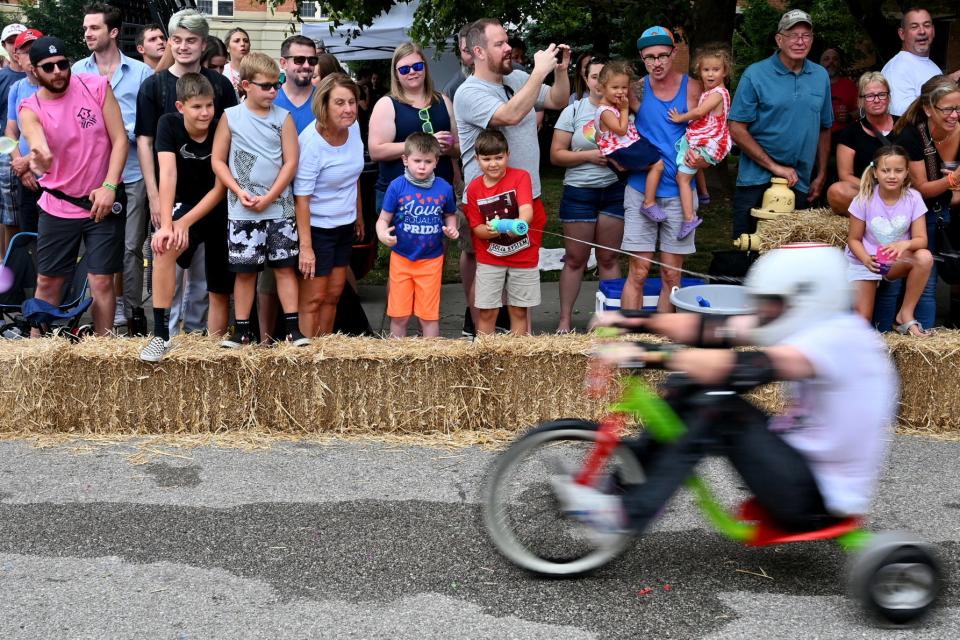 A child sprays a racer with a water gun on Saturday, July 31, 2021 at Danger Wheel, in the Pendleton area of Over-the-Rhine. Danger Wheel is an adult big-wheel race where proceeds are used to raise money for beautification efforts in the community.