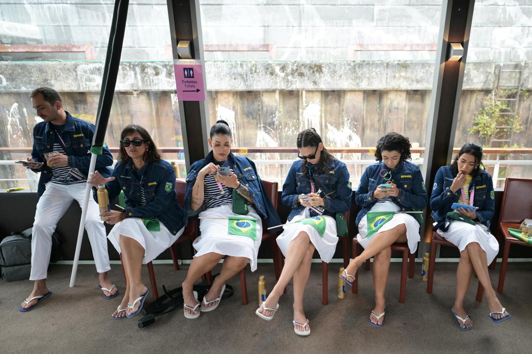 Members of the Brazilian delegation check their mobile phones   on their boat on the river Seine ahead of the opening ceremony of the Paris 2024 Olympic Games in Paris on July 26, 2024. (Photo by CARL DE SOUZA / POOL / AFP) (Photo by CARL DE SOUZA/POOL/AFP via Getty Images)