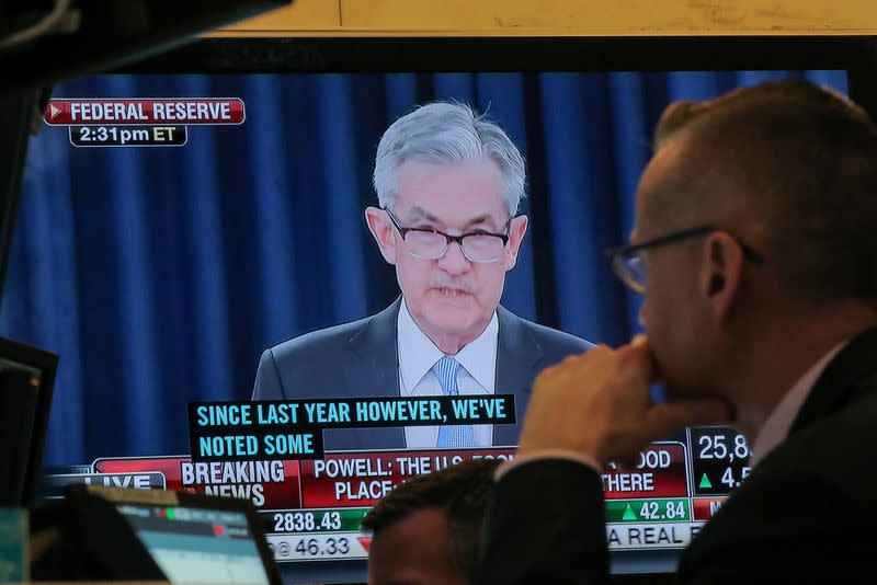 FILE PHOTO: A trader watches, U.S. Federal Reserve Chairman Jerome Powell on a screen on the floor at the NYSE in New York