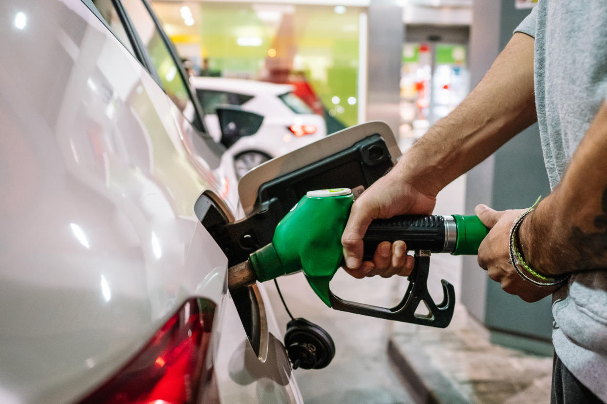 Unrecognizable male putting fuel dispenser in tank while refueling vehicle on self service gas station. High quality photo