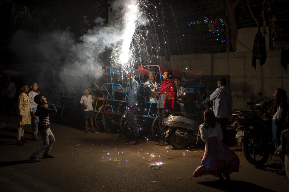 People watch a firecracker light up during Diwali celebrations in New Delhi, India, Thursday, Nov. 4, 2021. Millions of people across Asia are celebrating the Hindu festival of Diwali, which symbolizes new beginnings and the triumph of good over evil and light over darkness. (AP Photo/Altaf Qadri)