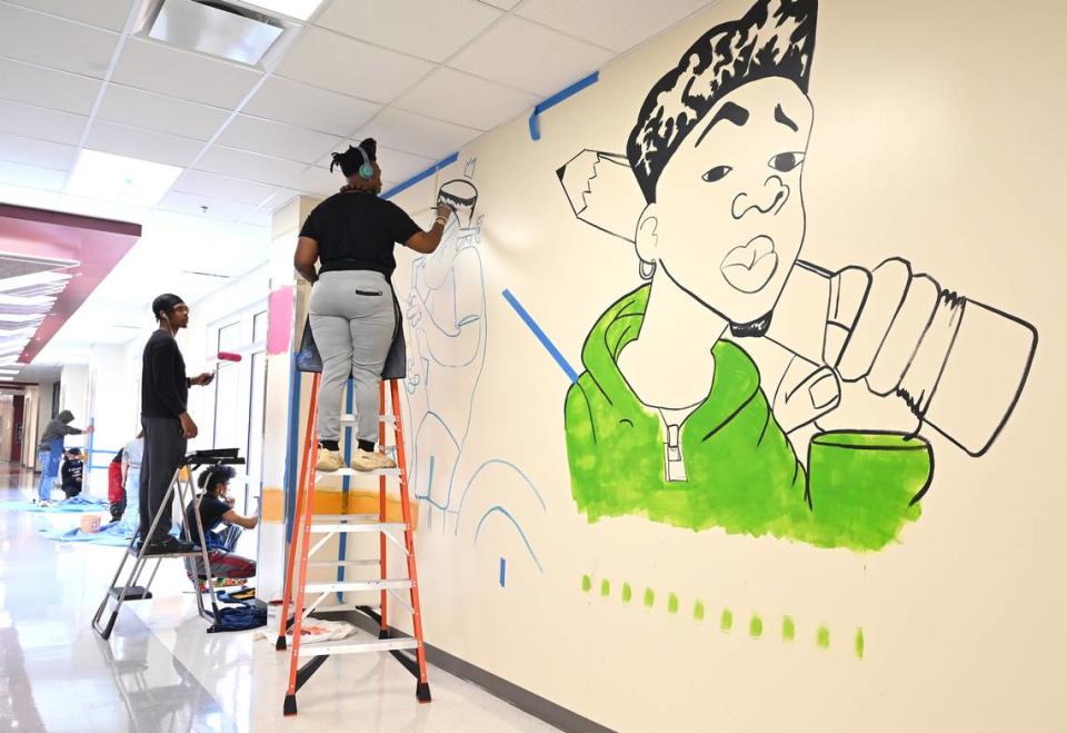 Local artist Michael Grant and West Charlotte High students work on a mural in a hallway of the new school on Tuesday, May 2, 2023.