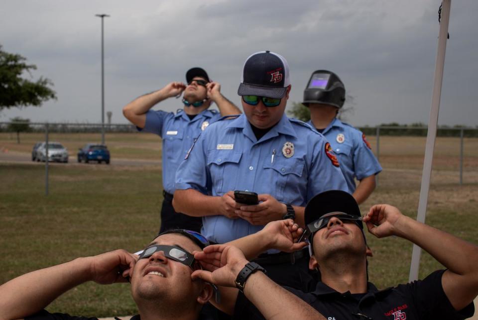 Firefighter EMTs watch the moon begin to cover the sun before a total eclipse in Eagle Pass on April 08, 2024.