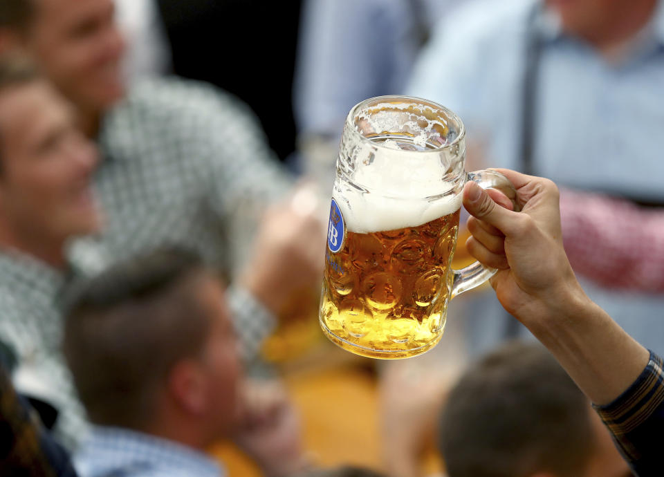 A guest holds glasses of beer during the opening of the 186th 'Oktoberfest' beer festival in Munich, Germany, Saturday, Sept. 21, 2019. (AP Photo/Matthias Schrader)