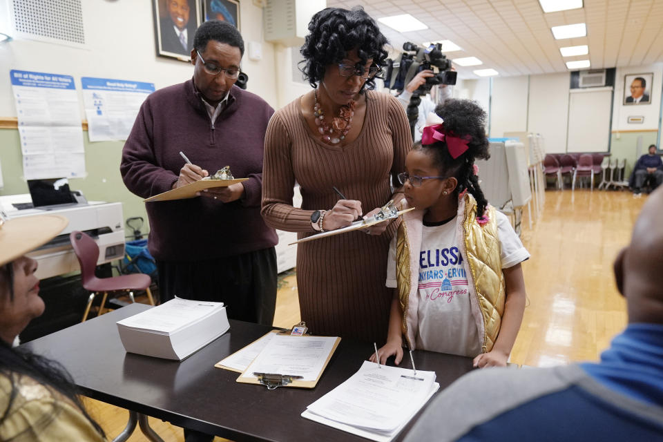 Chicago Treasurer Melissa Conyears-Ervin, center, who runs for Congress in IL-07, and her husband Jason Ervin, left, fill out voter registration form as her daughter Jeneva looks on at Marshall Metro high school in Chicago, Tuesday, March 19, 2024. Illinois residents will vote Tuesday to narrow Democratic and GOP candidate fields in key U.S. House races. (AP Photo/Nam Y. Huh)