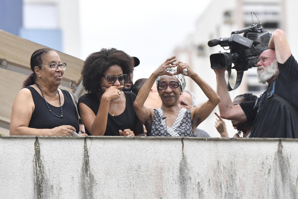Maria Lucia Nascimento, the sister of the late Brazilian soccer great Pele, signals a heart to people gathered outside her mother's home, during Pele's funeral procession from Vila Belmiro stadium to the cemetery in Santos, Brazil, Tuesday, Jan. 3, 2023. (AP Photo/Matias Delacroix)