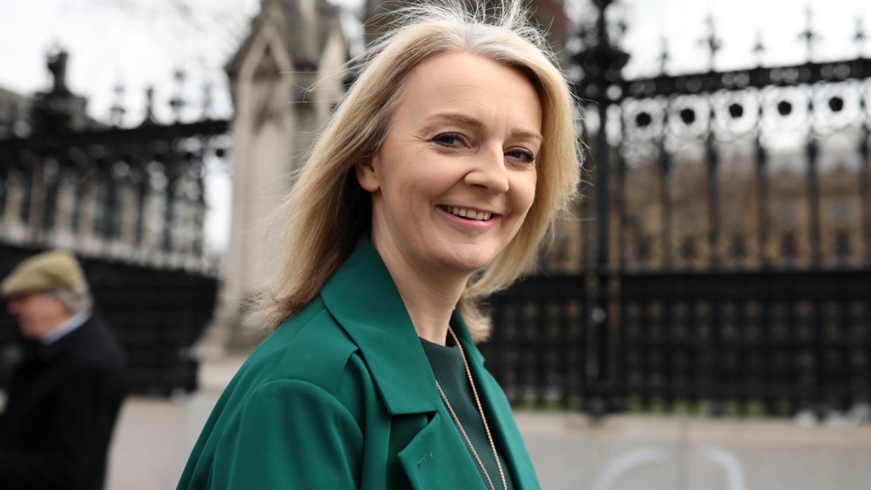 Elizabeth Truss in a green jacket, with the Houses of Parliament in the background.