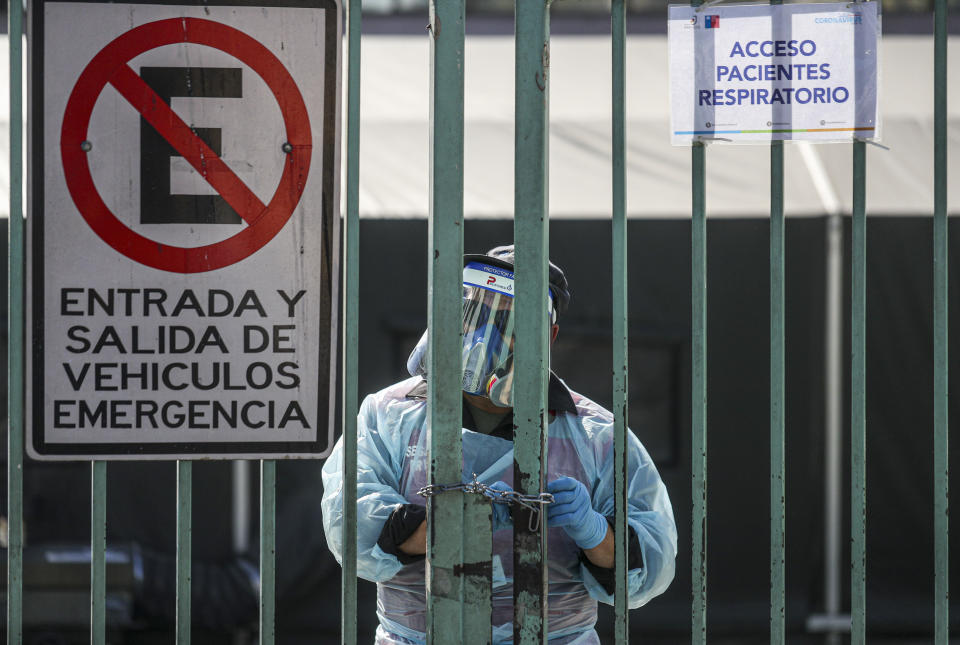 A health worker opens the gate leading to the field clinic where patients suspected of having the new coronavirus are treated at San Jose Hospital in Santiago, Chile, Friday, May 15, 2020. (AP Photo/Esteban Felix)