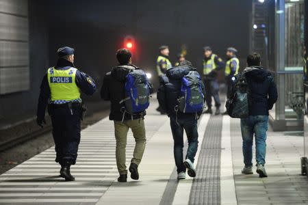 A police officer escorts migrants from a train at Hyllie station outside Malmo, Sweden, November 19, 2015. REUTERS/Johan Nilsson/TT NEWS AGENCY/File Photo