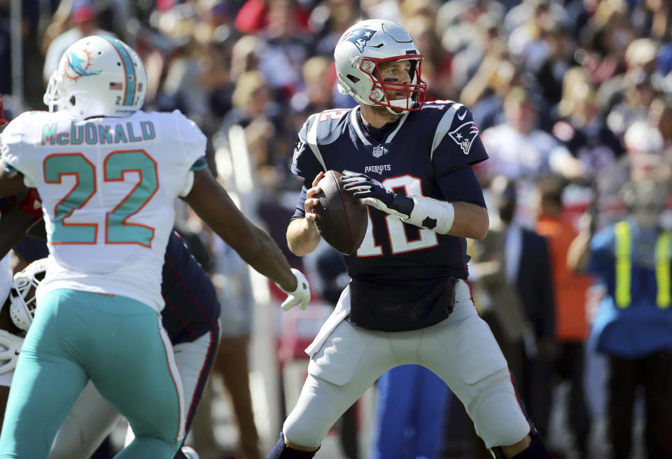 New England Patriots quarterback Tom Brady (12) looks for a receiver under pressure from Miami Dolphins defensive back T.J. McDonald (22) during the first half of an NFL football game, Sunday, Sept. 30, 2018, in Foxborough, Mass. (AP Photo/Elise Amendola)