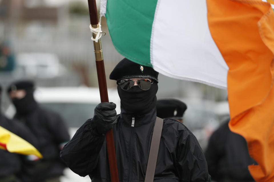 Un manifestante enmascarado sostiene una bandera irlandesa durante un desfile el lunes 10 de abril de 2023, en Londonderry, Irlanda del Norte. (AP Foto/Peter Morrison)