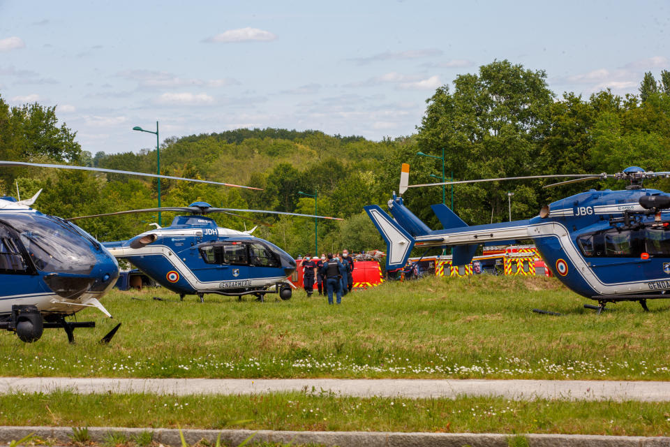 Gendarmes y bomberos franceses cerca de helicópteros en La Chapelle-sur-Erdre, Francia, el viernes 28 de mayo de 2021, luego de que momentos antes un hombre no identificado apuñaló a un policía en su estación y luego baleó a otros dos agentes antes de morir en un tiroteo con los agentes. (AP Foto/Laetitia Notarianni)