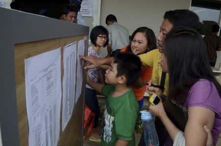 Family members of passengers on board AirAsia flight QZ 8501 look at a passenger list inside a crisis centre at Juanda Airport in Surabaya, East Java December 28, 2014 in this photo taken by Antara Foto. REUTERS/Antara Foto/Suryanto