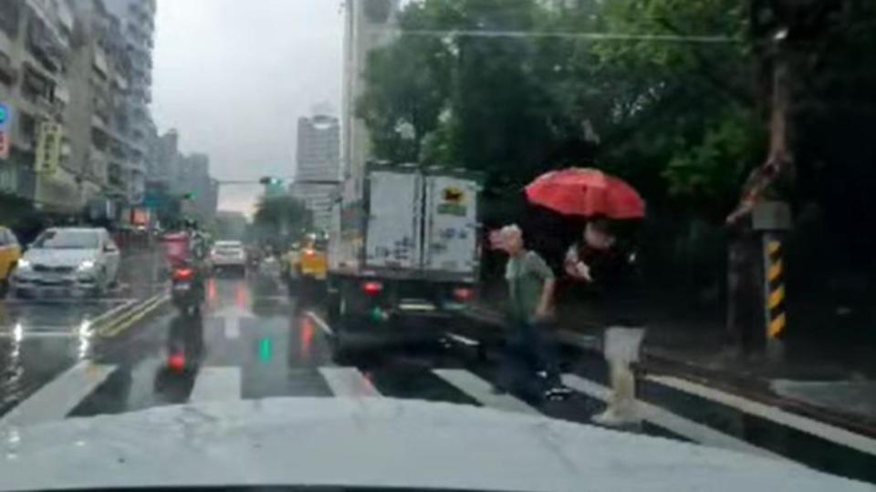 黑衣男熱心撐傘替阿嬤擋雨，並攙扶對方過馬路。（圖／翻攝自爆怨2公社臉書）