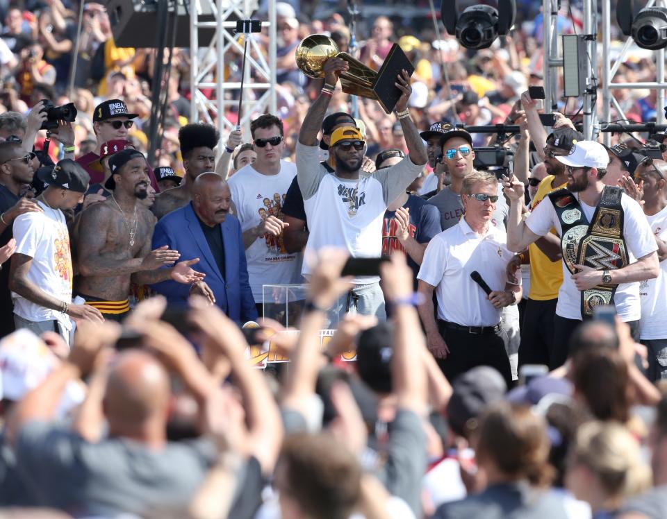 LeBron James raises the Larry O'Brien Trophy with Jim Brown by his side at the  rally following the Cavaliers' NBA Championship Parade in Cleveland on Tuesday, June 21, 2016.