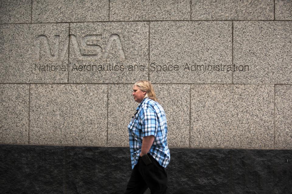 A woman walks past the NASA headquarters on Tuesday morning after the federal government was shutdown when the House and Senate failed to pass a budget in Washington October 1, 2013. The lawmakers who shut down the U.S. government on Tuesday have the best view of the result from their perch in the U.S. Capitol: a two-mile stretch of museums, monuments and federal buildings along the National Mall that were closed for business. REUTERS/James Lawler Duggan (UNITED STATES - Tags: POLITICS BUSINESS)