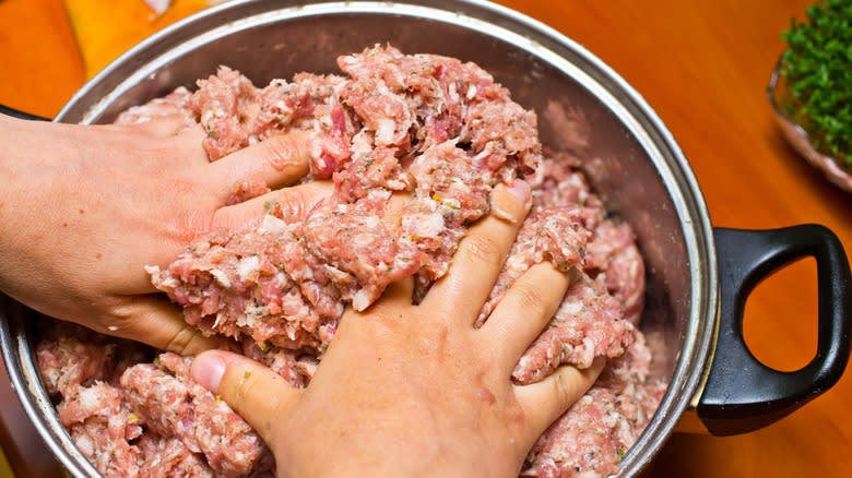 mixing raw sausage with hands