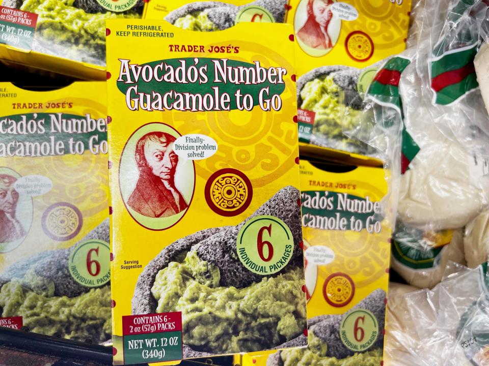 Yellow boxes of Trader Joe's avocado's number guacamole to go with an image of guacamole in a molcajete