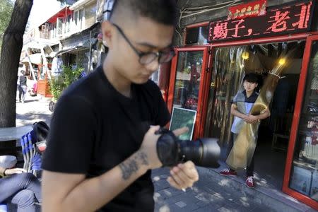 Chinese artist ROBBBB prepares to take pictures of people along a street for his artworks in Beijing's Gulou area, September 25, 2015. REUTERS/Jason Lee