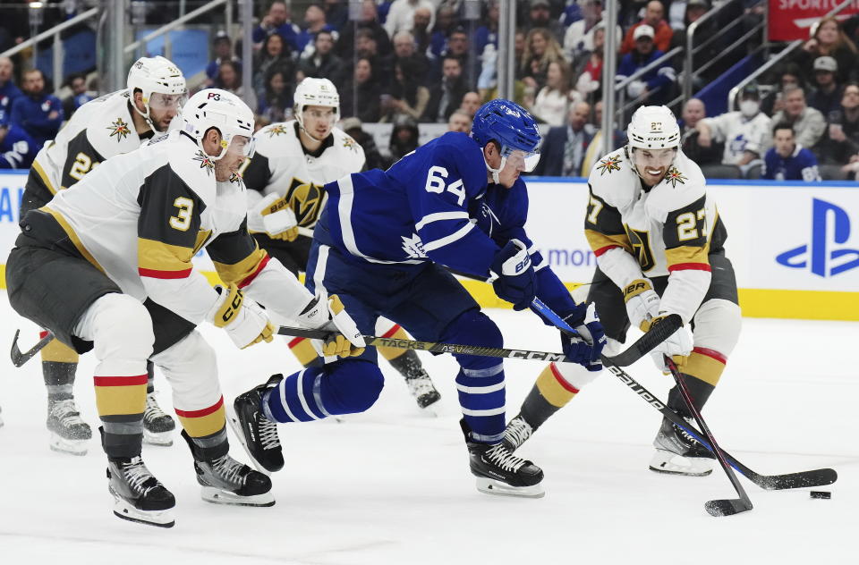 Toronto Maple Leafs forward David Kampf (64) carries the puck between Vegas Golden Knights defenseman Brayden McNabb (3) and defenseman Shea Theodore (27) during the second period of an NHL hockey game, Tuesday, Nov. 8, 2022 in Toronto. (Nathan Denette/The Canadian Press via AP)