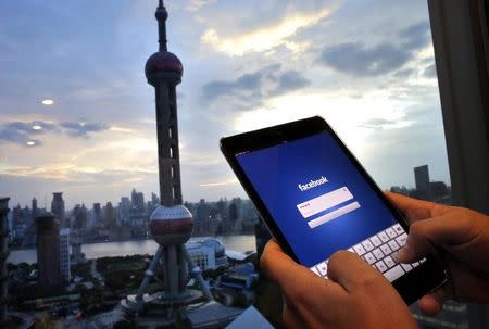 In this photo illustration, a man holds an iPad with a Facebook application in an office building at the Pudong financial district in Shanghai, September 25, 2013. REUTERS/Carlos Barria